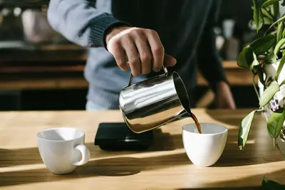 Close-up of coffee being poured into a white cup, creating beautiful latte art patterns